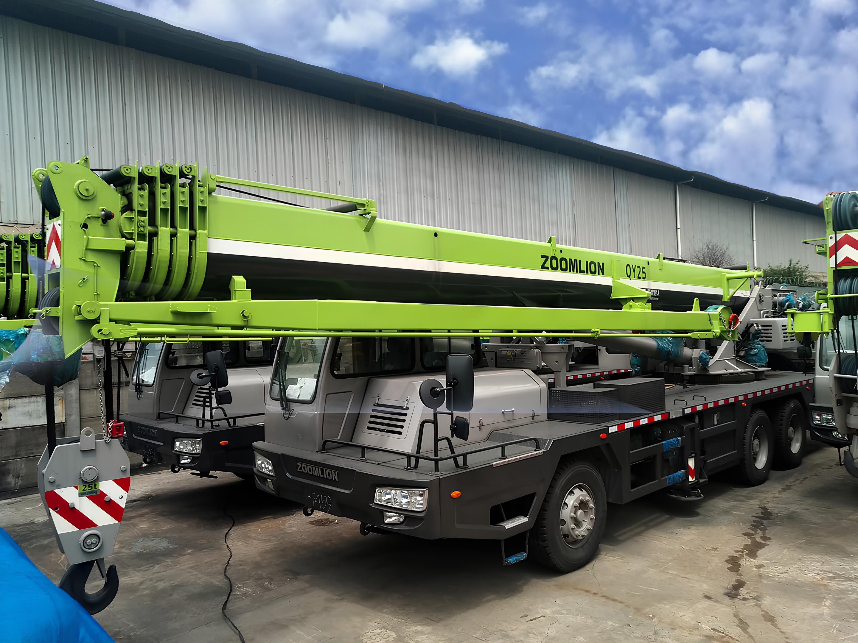 Xe cẩu bánh lốp Zoomlion QY25 25 tấn màu trắng và vàng đặc trưng đang vươn cần mạnh mẽ tại một công trường, sẵn sàng cho công việc nâng hạ.