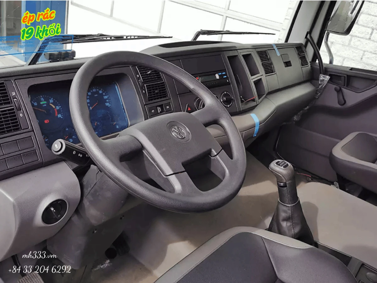 Cabin xe ép rác Alpha 19 nhìn từ ghế phụ, vô lăng có logo Volkswagen, đồng hồ hiển thị và cần số sàn