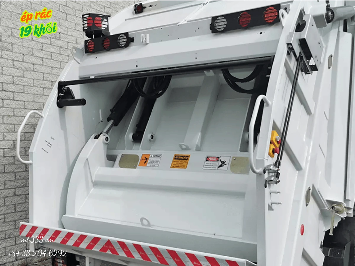 Cận cảnh miệng nạp rác phía sau xe ép rác Alpha 19 khi cửa sau nâng lên, thấy rõ xi lanh thủy lực và tem cảnh báo