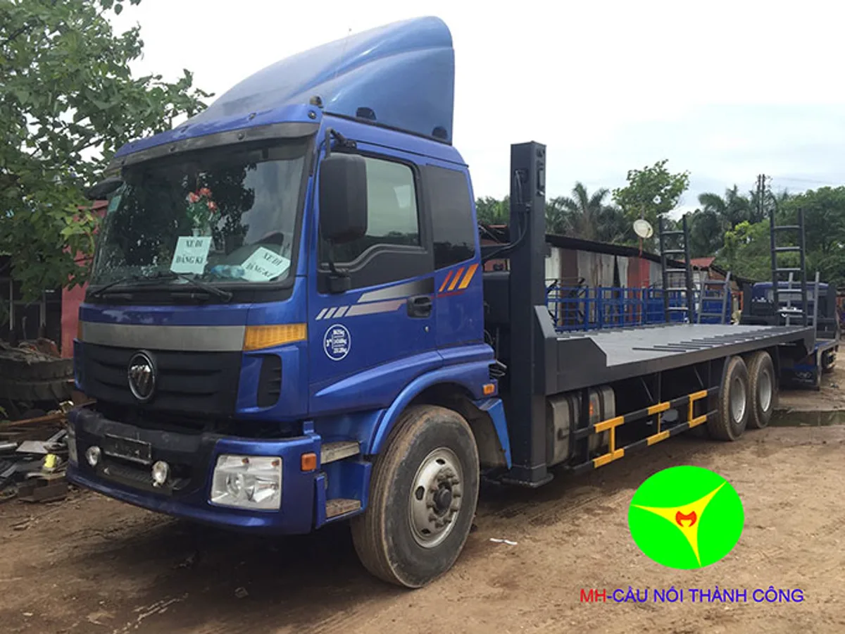 Xe nâng đầu Thaco Auman 3 chân màu xanh với sàn chở máy và ba trục phía sau