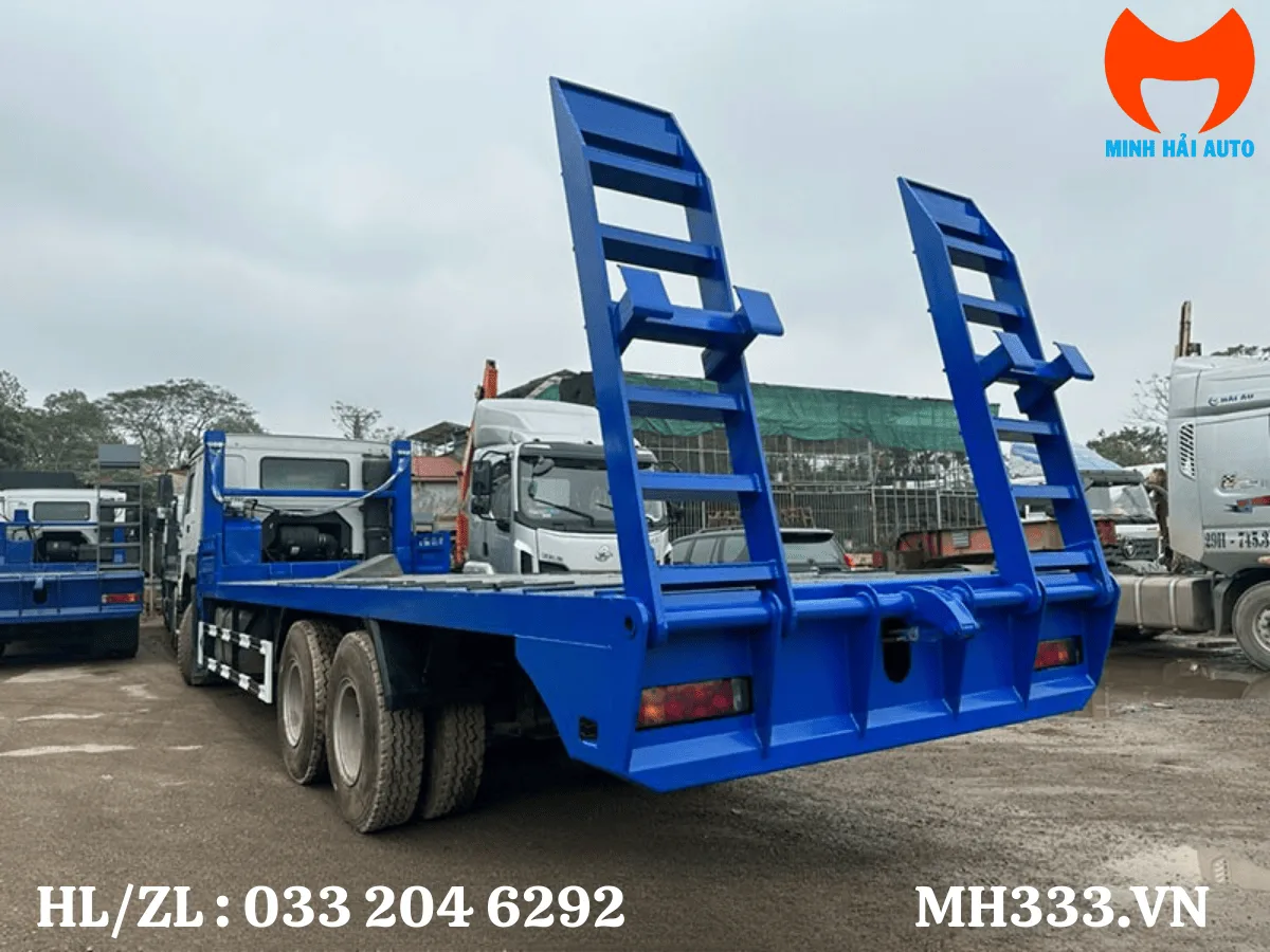 Xe nâng đầu HOWO 3 chân nhìn từ phía sau với sàn chở máy và hai cầu dẫn gập dựng đứng