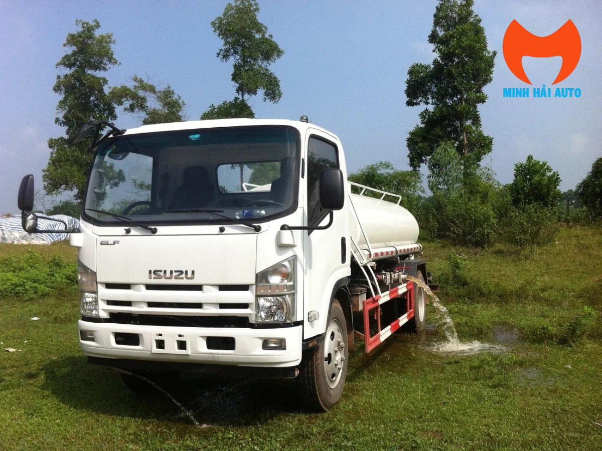 Xe bồn phun nước Isuzu cabin trắng nhìn từ góc trước, vòi bên hông đang xả nước