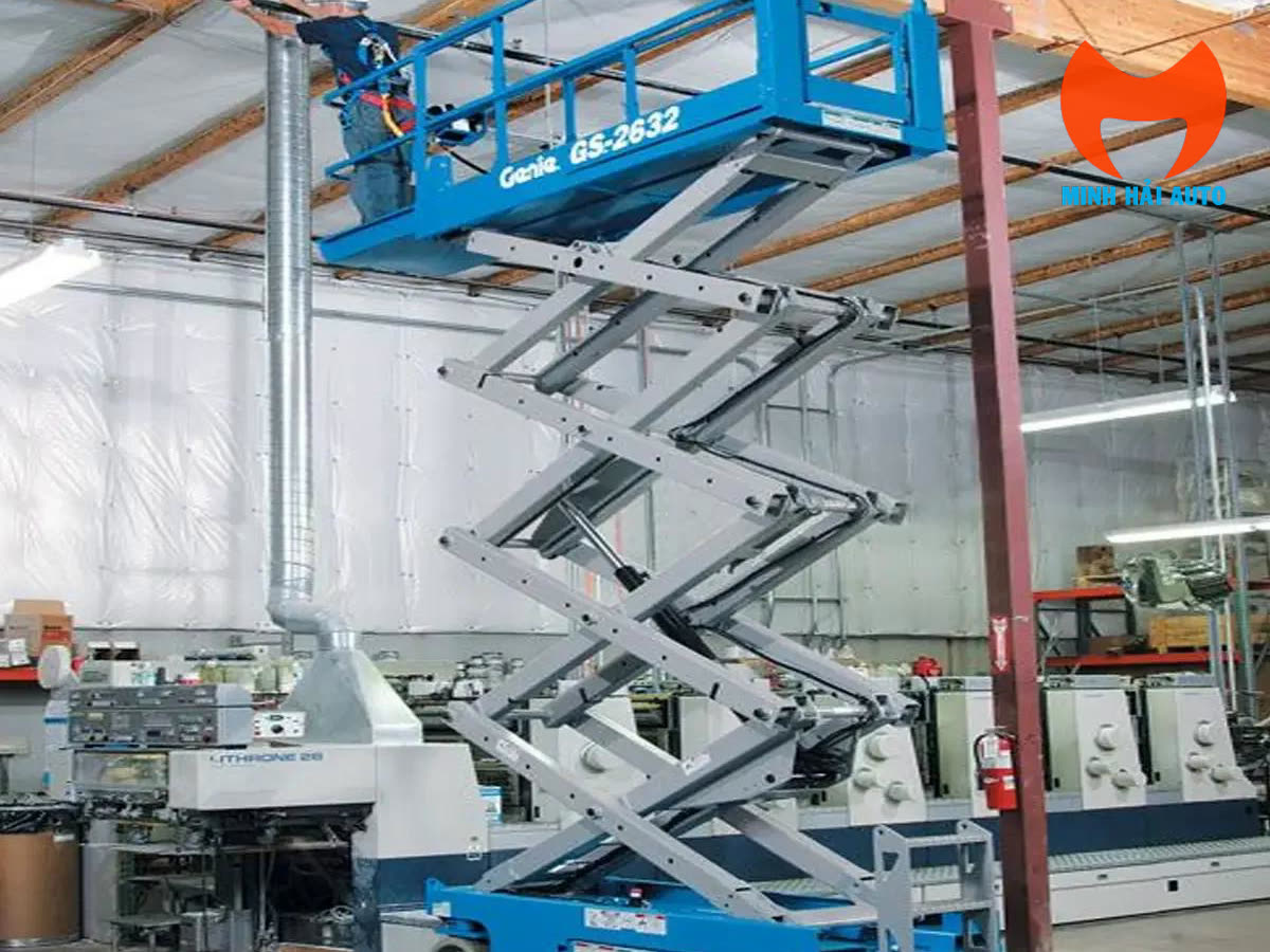 Xe nâng người cắt kéo làm việc trong nhà xưởng trên nền bằng phẳng
