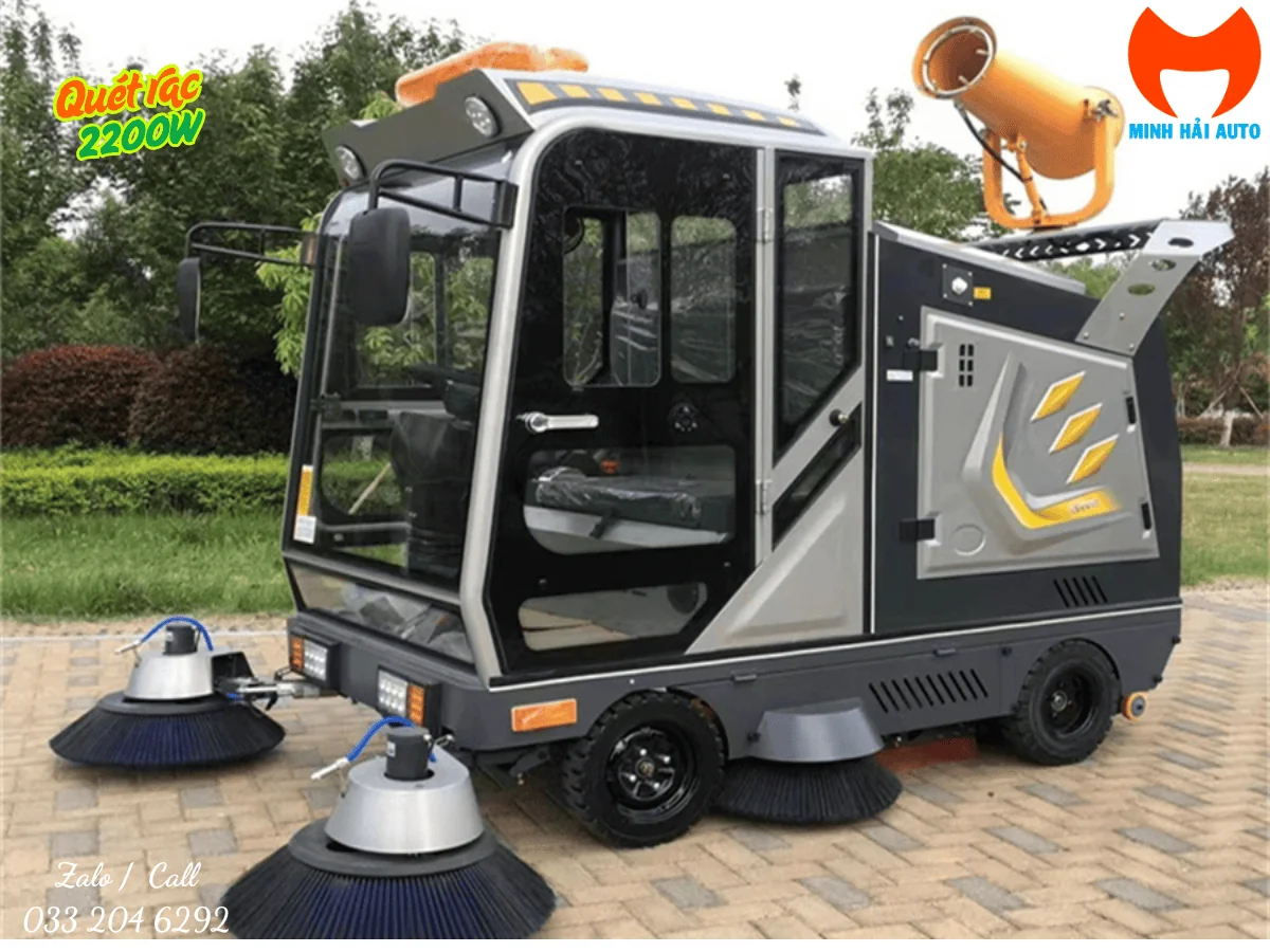 Xe quét rác ngồi lái màu xám, cabin kính và hai chổi phía trước nhìn từ góc ba phần tư