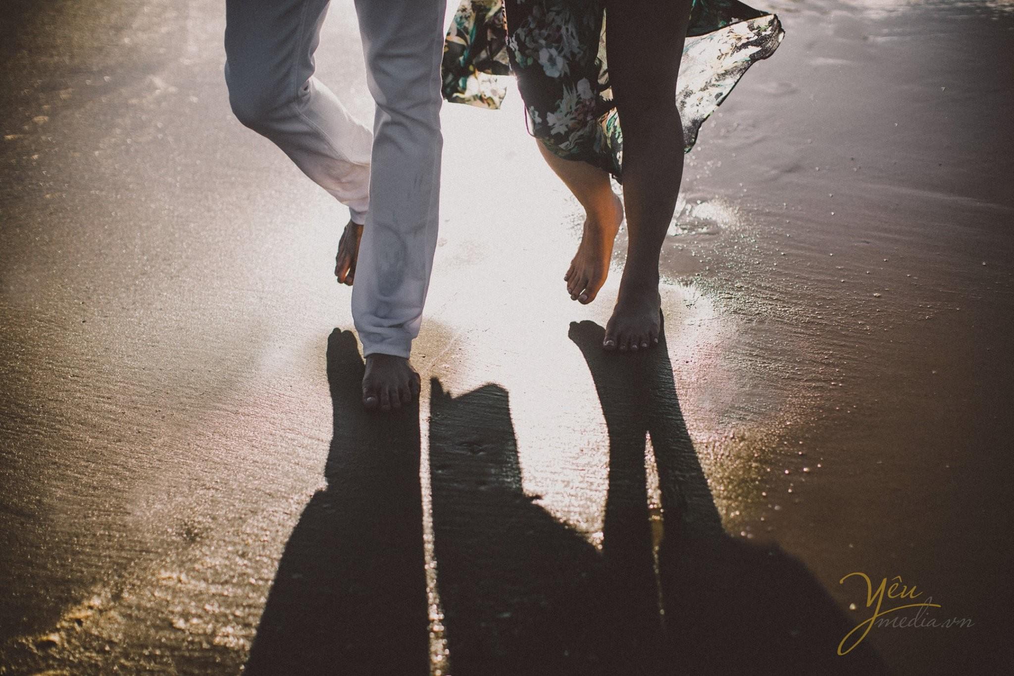 ảnh chụp chân chần trên cát biển nắng chiều và thủy chiều lên in bóng 2 người