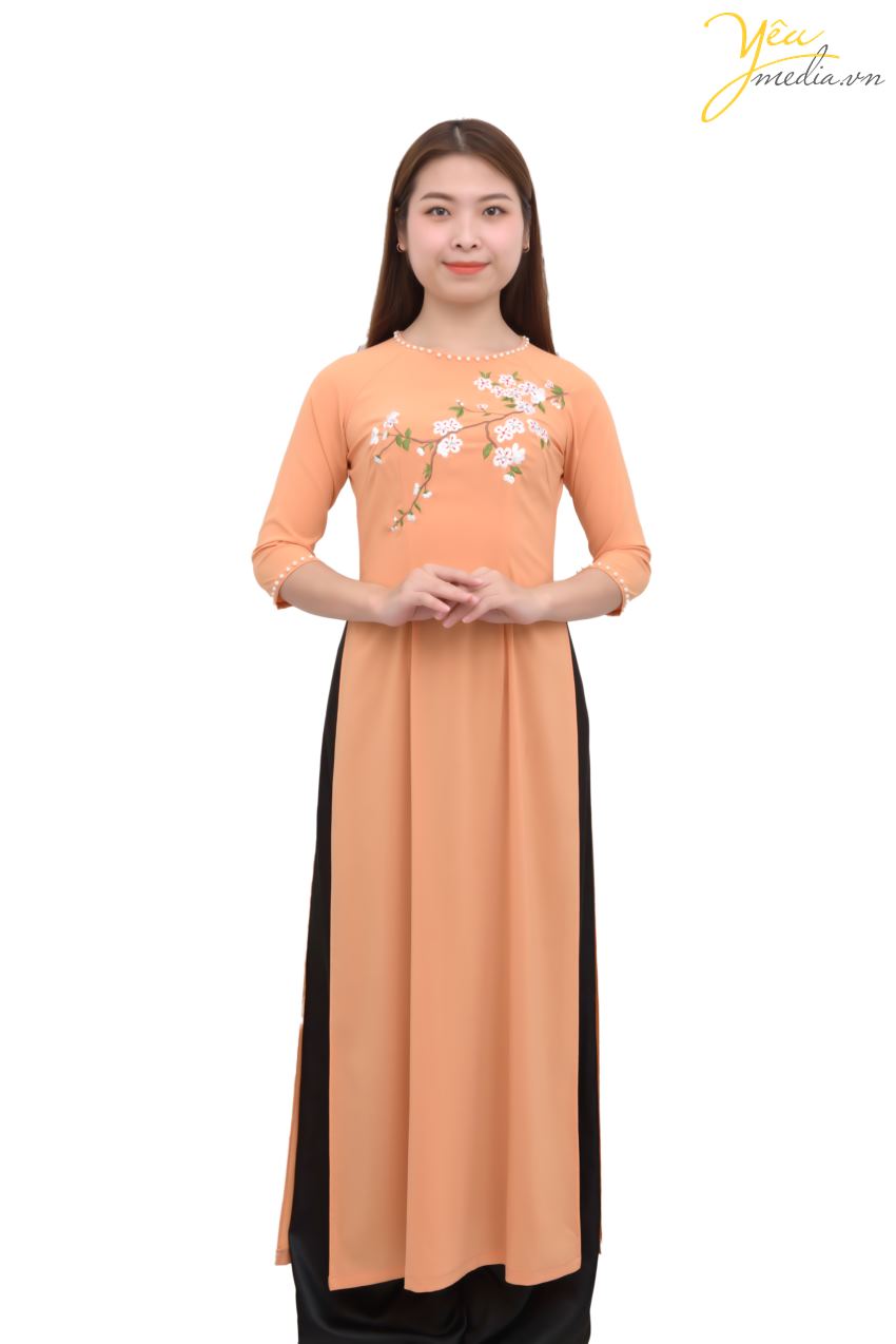 Bộ áo dài 80 có màu sắc cam tươi sáng, tay lỡ, viền cổ áo và viền tay áo là những hạt ngọc quý phái, điểm xuyết những nhành hoa nhẹ nhàng trên thân áo - tất cả đã tạo nên 1 bản hòa ca nhẹ nhàng, thanh khiết cho trang phục này. Đây là bộ áo dài được các chị, các cô 30 - 40 tuổi ưa thích. 