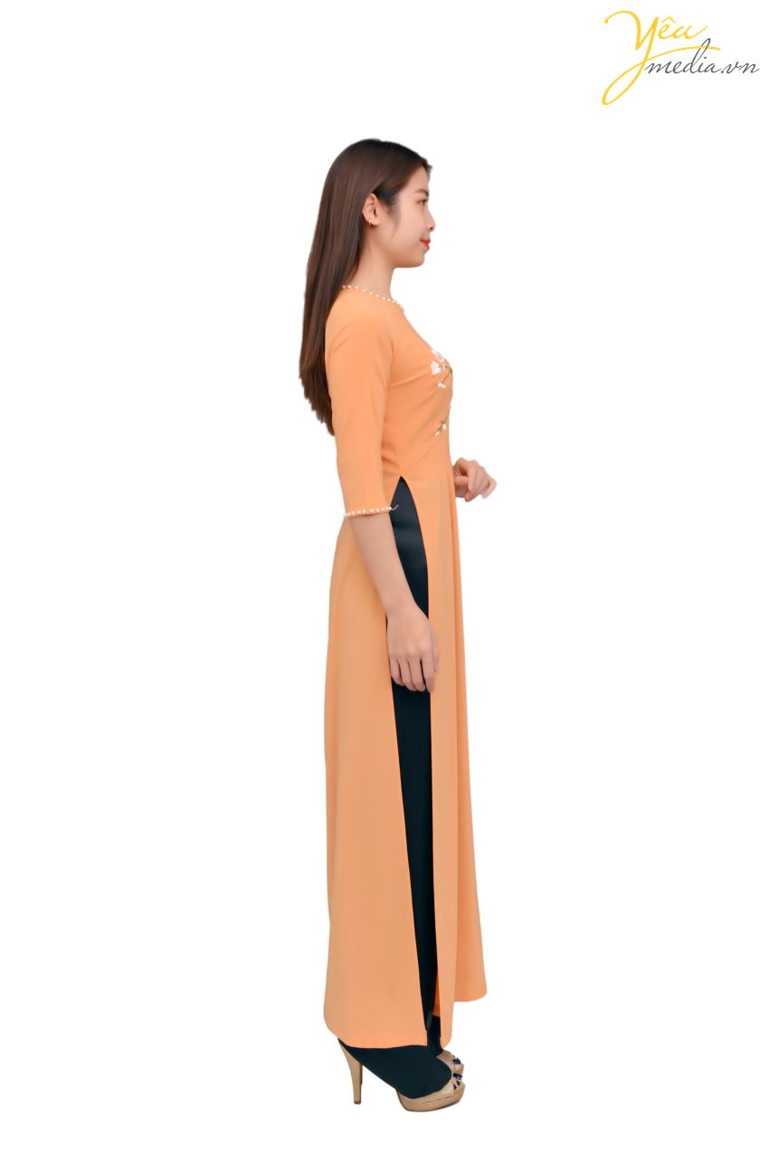 Bộ áo dài 80 có màu sắc cam tươi sáng, tay lỡ, viền cổ áo và viền tay áo là những hạt ngọc quý phái, điểm xuyết những nhành hoa nhẹ nhàng trên thân áo - tất cả đã tạo nên 1 bản hòa ca nhẹ nhàng, thanh khiết cho trang phục này. Đây là bộ áo dài được các chị, các cô 30 - 40 tuổi ưa thích. 