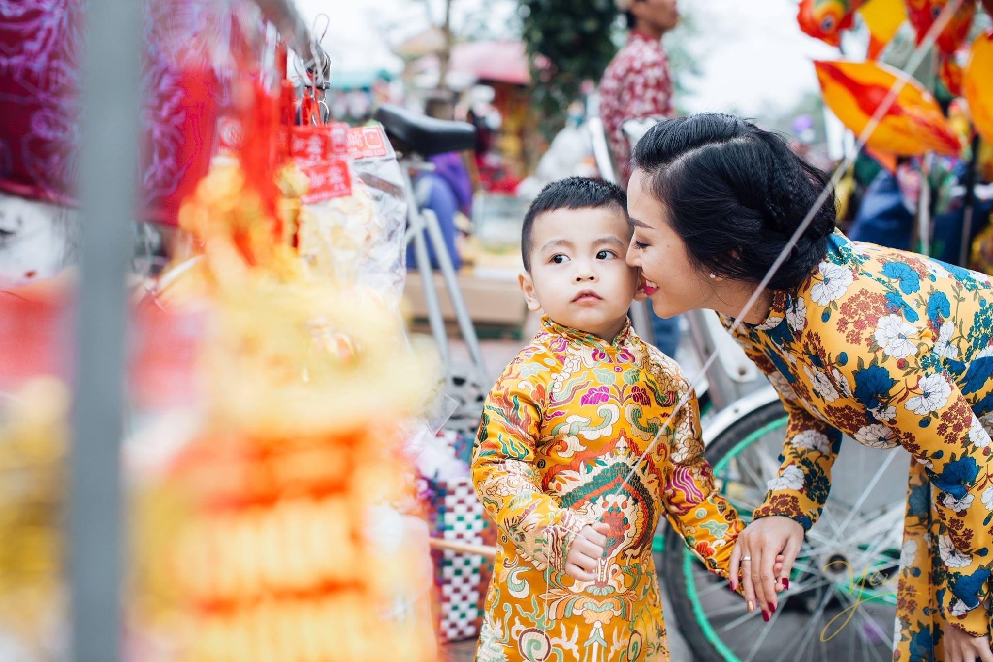 bé chụp ảnh áo dài tết với mẹ cạnh quầy bán lì xì, bóng bay