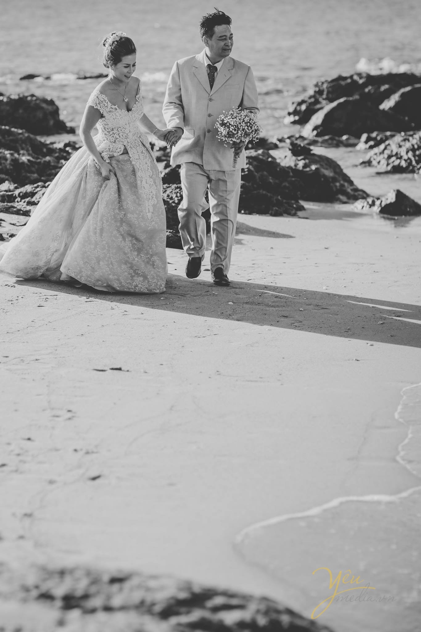 cặp đôi dắt tay nhau đi trên bờ cát trắng 