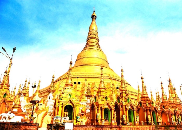 Kết quả hình ảnh cho Chùa Vàng ở Yangon là ngôi chùa linh thiêng bậc nhất ở Myanmar. Tương truyền rằng nơi đây có lưu giữ 4 báu vật của Phật giáo là: Cây gậy của Phật Câu Lưu Tôn, mảnh áo của Phật Ca Diếp, lọc nước của Phật Câu Na Hàm và 8 sợi tóc của Phật Thích Ca Mâu Ni. Không chỉ cổ kính thiêng liêng mà nơi đây còn là điểm du lịch đẹp nổi tiếng ở Myanmar bởi lối kiến trúc vô cùng độc đáo và bắt mắt. Cổng vào chùa Vàng Myanmar với cặp Tỳ Hưu khổng lồ cao 9m ở hai bên Chùa có toàn bộ hệ thống nội thất được trạm trổ vô cùng cầu kỳ và tỷ mỷ với 8.690 lá vàng dát cực mỏng, toàn bộ ngôi chùa được điểm tô thêm phần lung linh ảo diệu với 5.450 viên kim cương đủ kích cỡ và 2.320 viên hồng ngọc, lam ngọc. Ngôi chùa biểu tượng của sự linh thiêng đất nước Myanmar này sẽ làm bạn vô cùng thích thú bởi màu sắc của nó biến hoa đa dạng tùy vào từng thời điểm trong ngày.