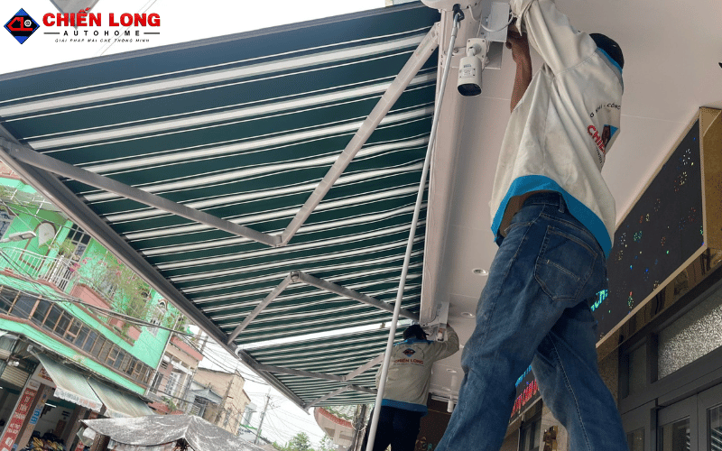 Kỹ thuật viên căn chỉnh mái hiên tự động sọc xanh trắng tại công trình Tiền Giang