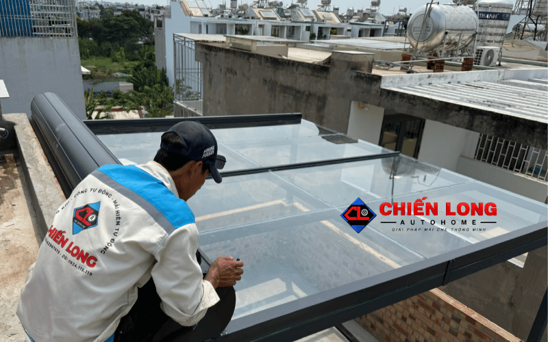 Thợ thi công kiểm tra ray trượt mái nhôm cuốn tự động trên mái kính.