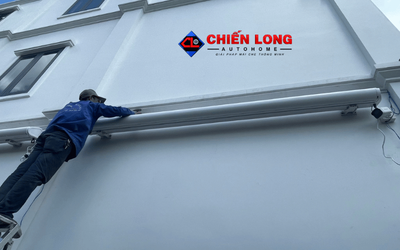 Kỹ thuật viên lắp đặt mái hiên tự động trên tường bên hông nhà tại Long An