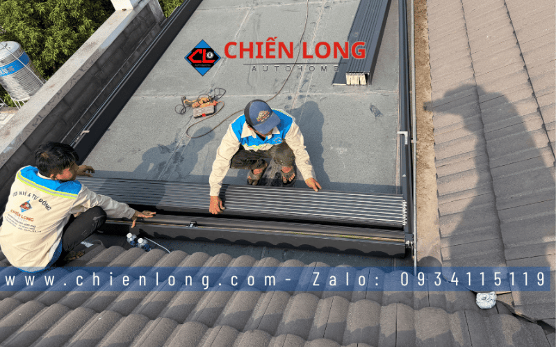 Hai kỹ thuật viên phối hợp lắp cụm lá nhôm xếp trượt tại đầu khung mái.