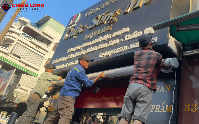 Đội ngũ kỹ thuật lắp hộp mái hiên tự động dưới bảng hiệu cửa hàng tại Quận 10