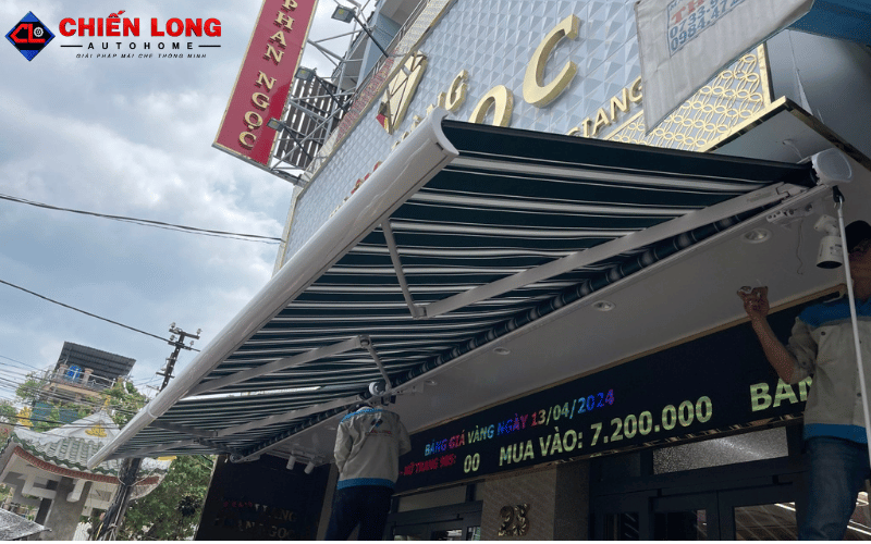Khung và tay đỡ màu trắng bên dưới mái hiên vải sọc xanh trắng tại Tiền Giang