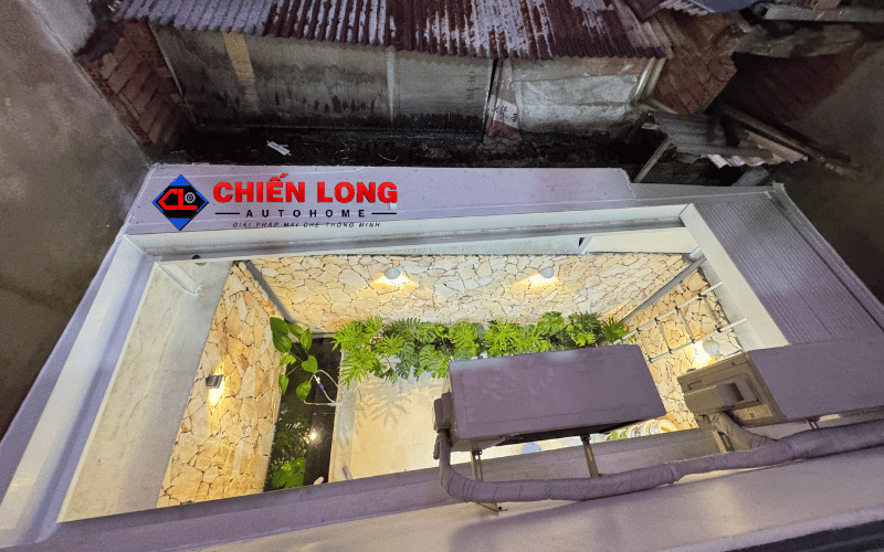 Mái nhôm Ziczac màu trắng hệ chống nước thu gọn trên giếng trời có bàn ghế và cây xanh.