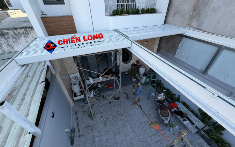 Toàn cảnh mái nhôm Ziczac màu trắng thu gọn gần mặt tiền, để mở khoảng sân
