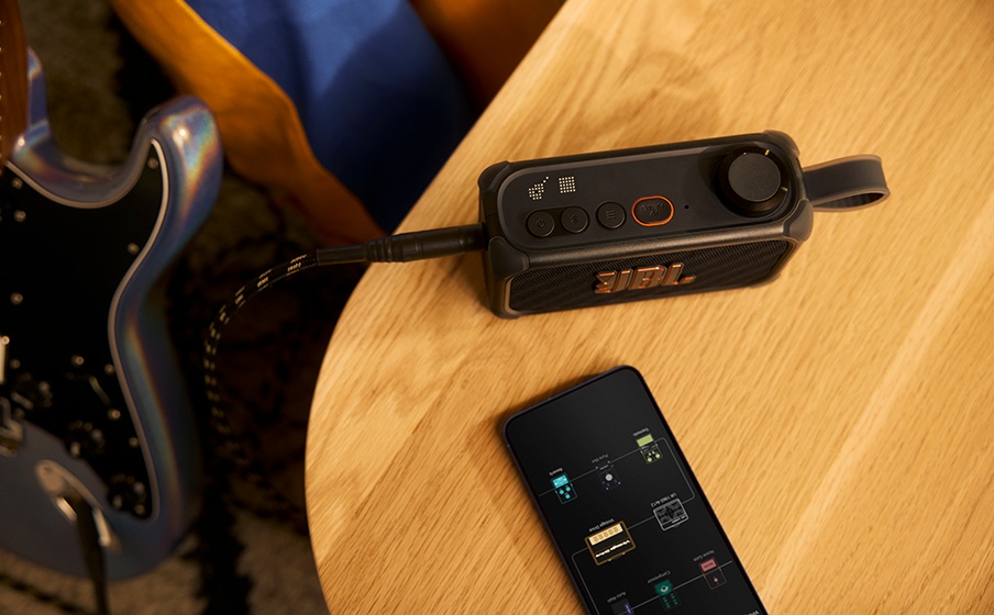 JBL BandBox Solo bên guitar và điện thoại trên bàn tập