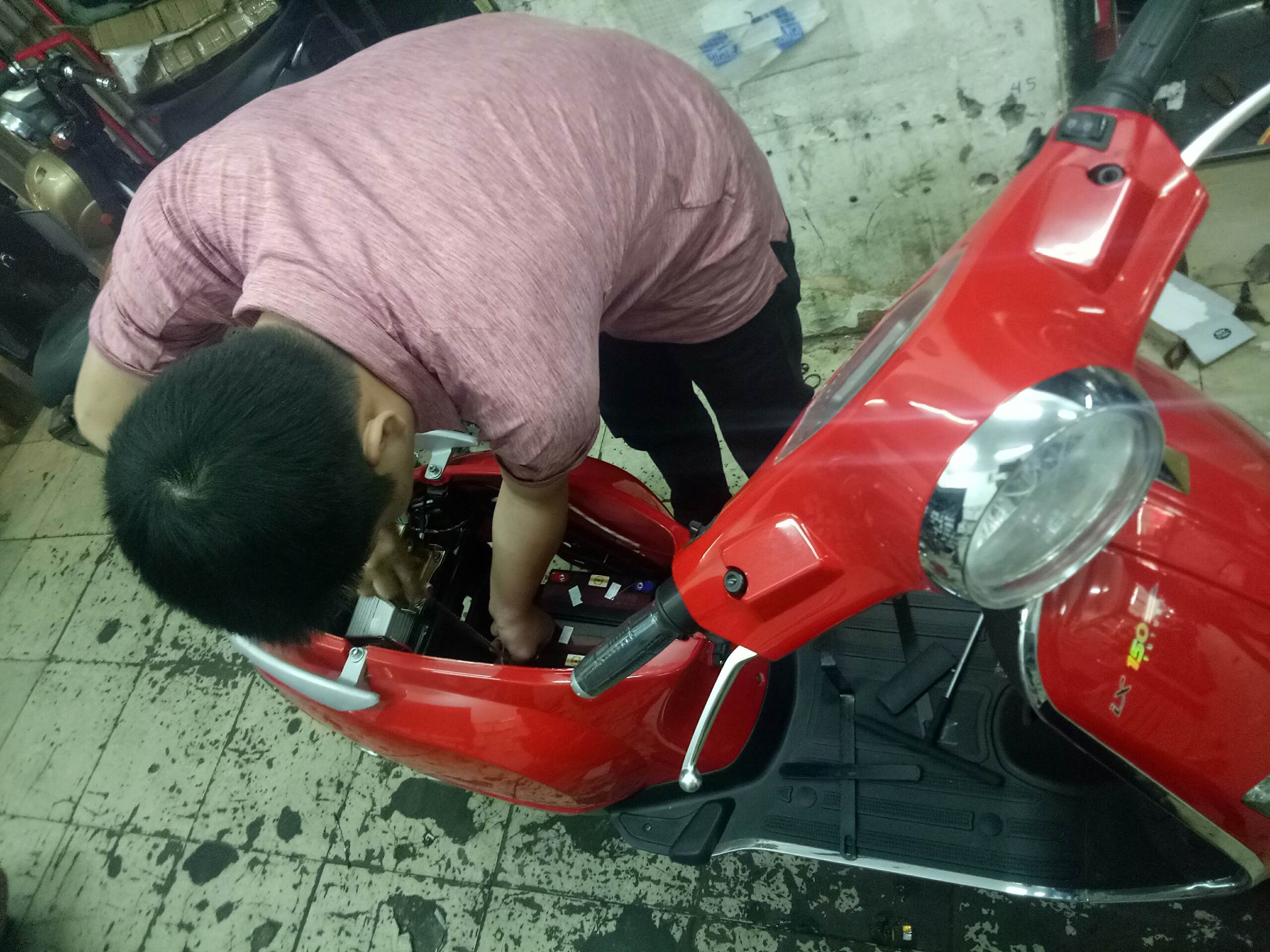 kĩ thuật viên đang lắp ắc quy cho xe máy điện Vespa 