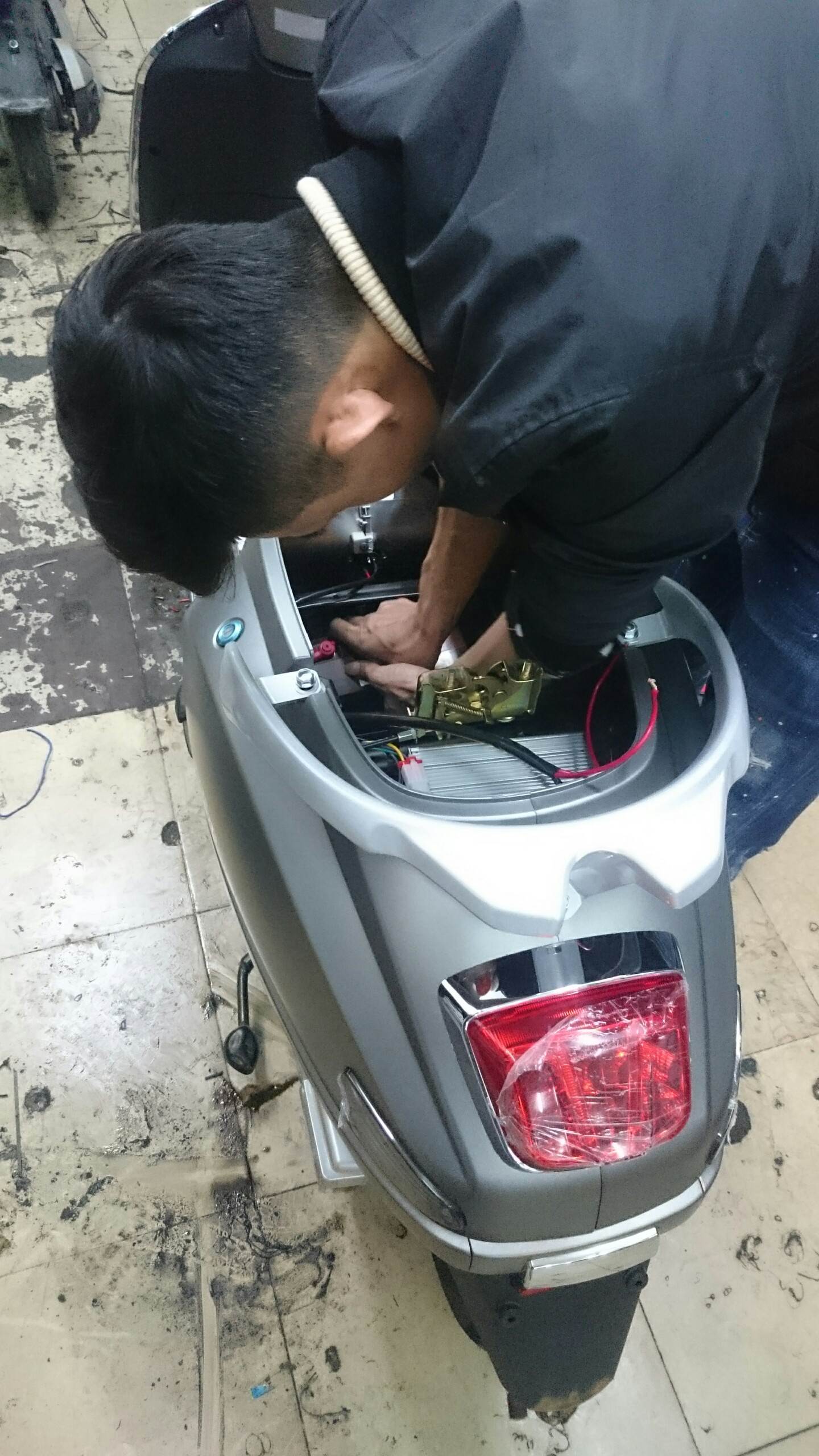 kĩ thuật viên đang thay ắc quy cho xe máy điện Vespa 