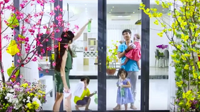 Gia đình trong nhà có người đang lau dọn giữa những cành hoa Tết