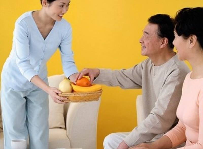 Người giúp việc mang khay trái cây phục vụ một cặp vợ chồng lớn tuổi