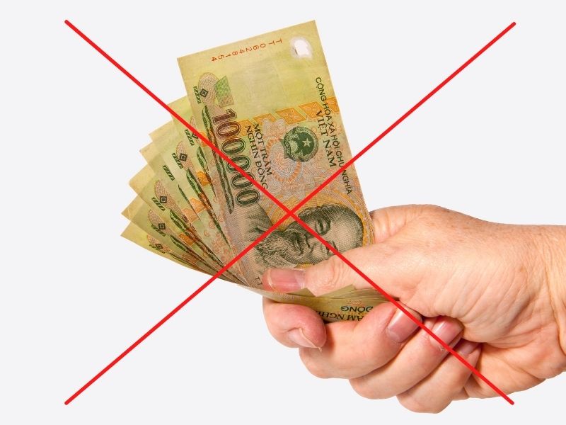 Bàn tay cầm nhiều tờ tiền Việt Nam với dấu gạch đỏ