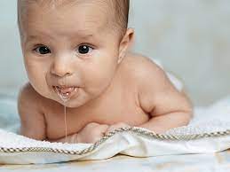 Em bé nằm sấp trên chăn, có sữa chảy quanh miệng