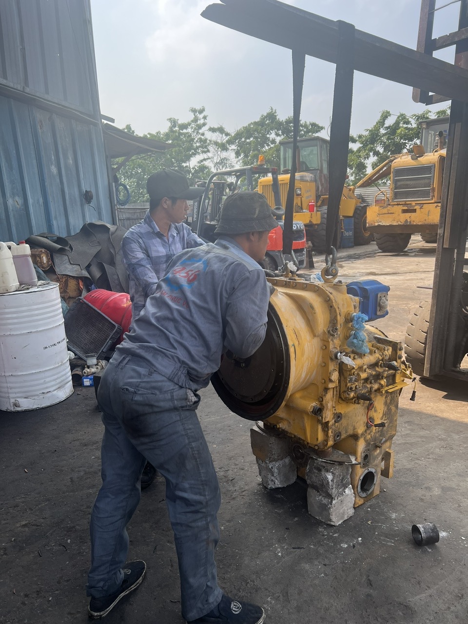 Đội ngũ thợ cơ khí đang tiến hành rã ráp và cẩu tách cụm hộp số máy xúc lật thủy lực