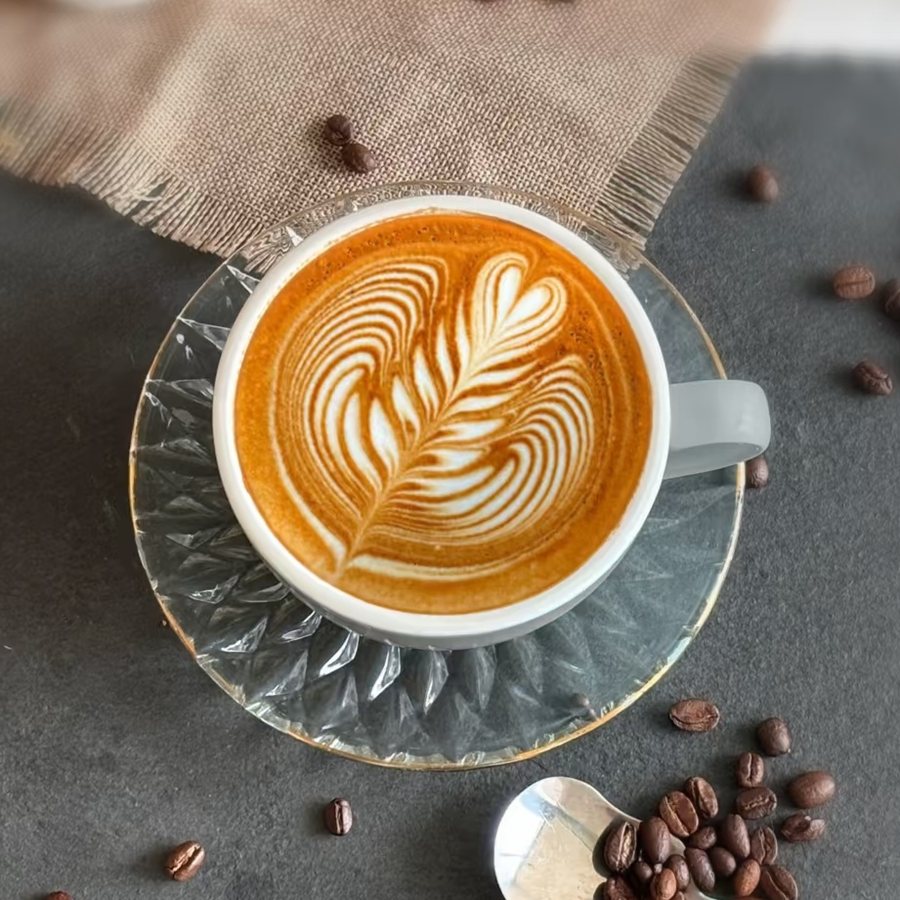 Latte art hình rosetta lá dương xỉ với các nhánh đều hai bên, tạo bằng lắc cổ tay đều nhịp