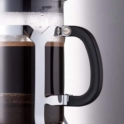Cận cảnh tay cầm nhựa đen và khung inox của bình French Press với lớp bã cà phê bị ép xuống