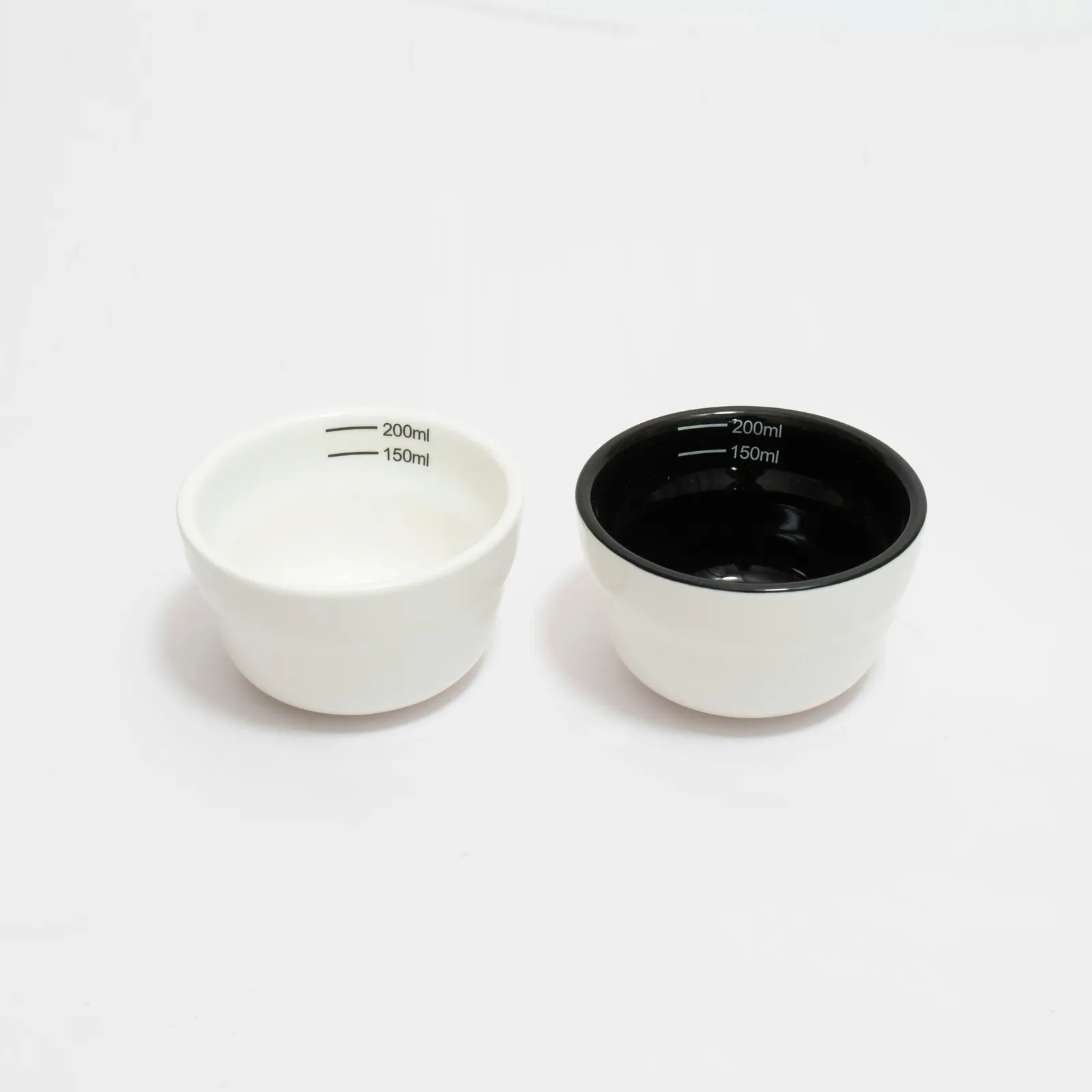 Hai chén sứ cupping thử nếm cà phê một lòng trắng một lòng nâu đặt cạnh nhau