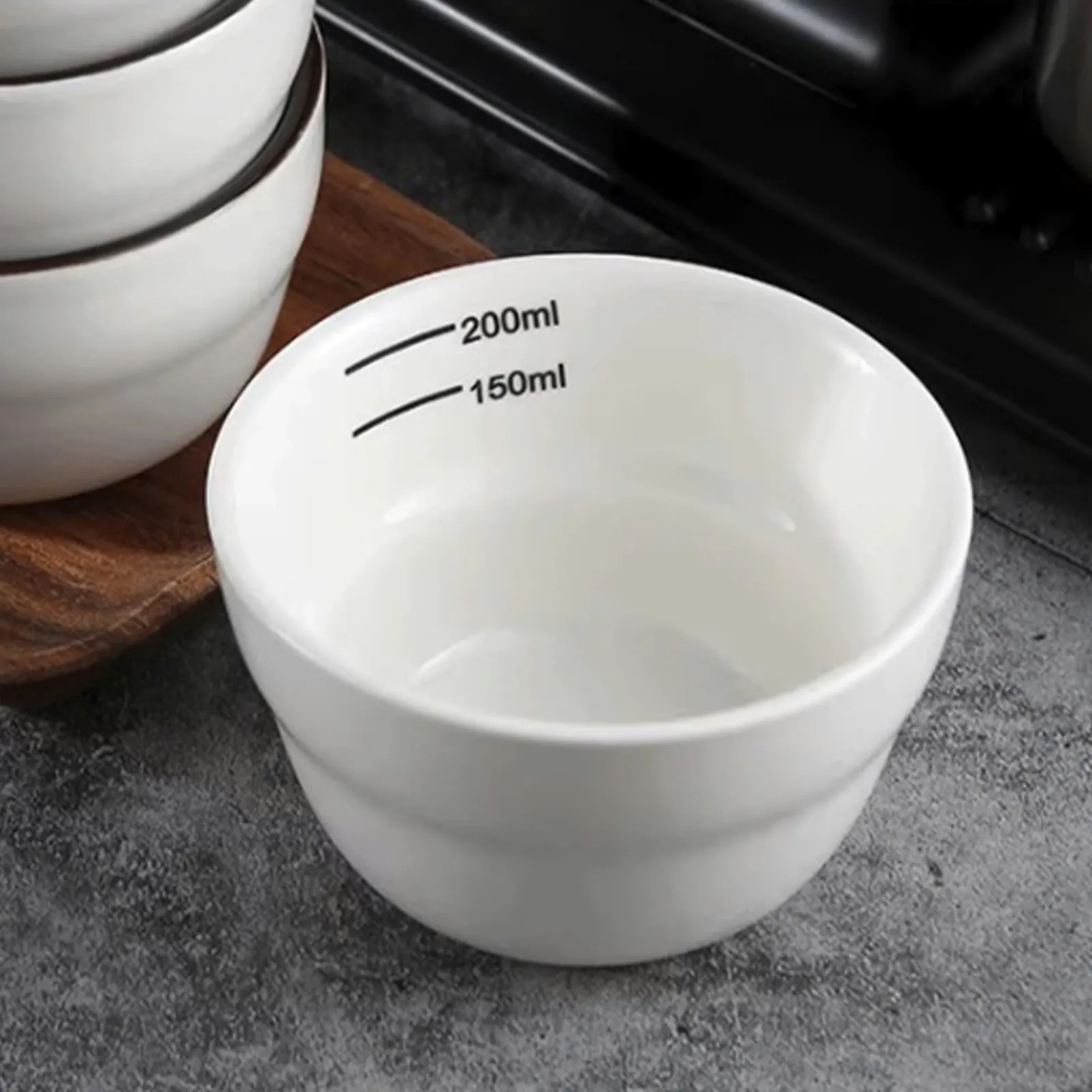 Ba chén cupping đặt trên bàn bếp cạnh máy pha cà phê và hai muỗng cupping