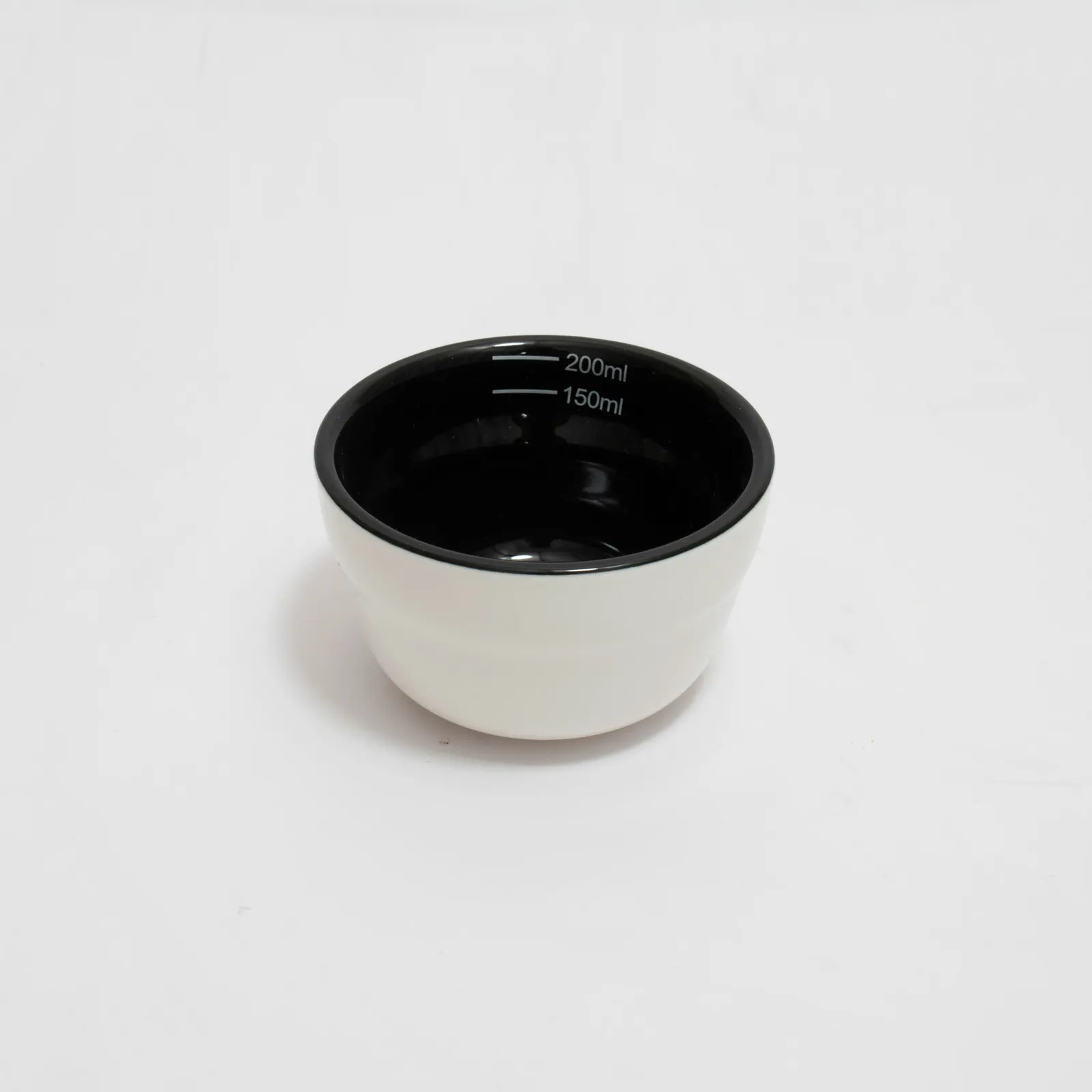 Rót nước nóng từ ấm cổ ngỗng vào chén cupping đựng bột cà phê đặt trên đế gỗ