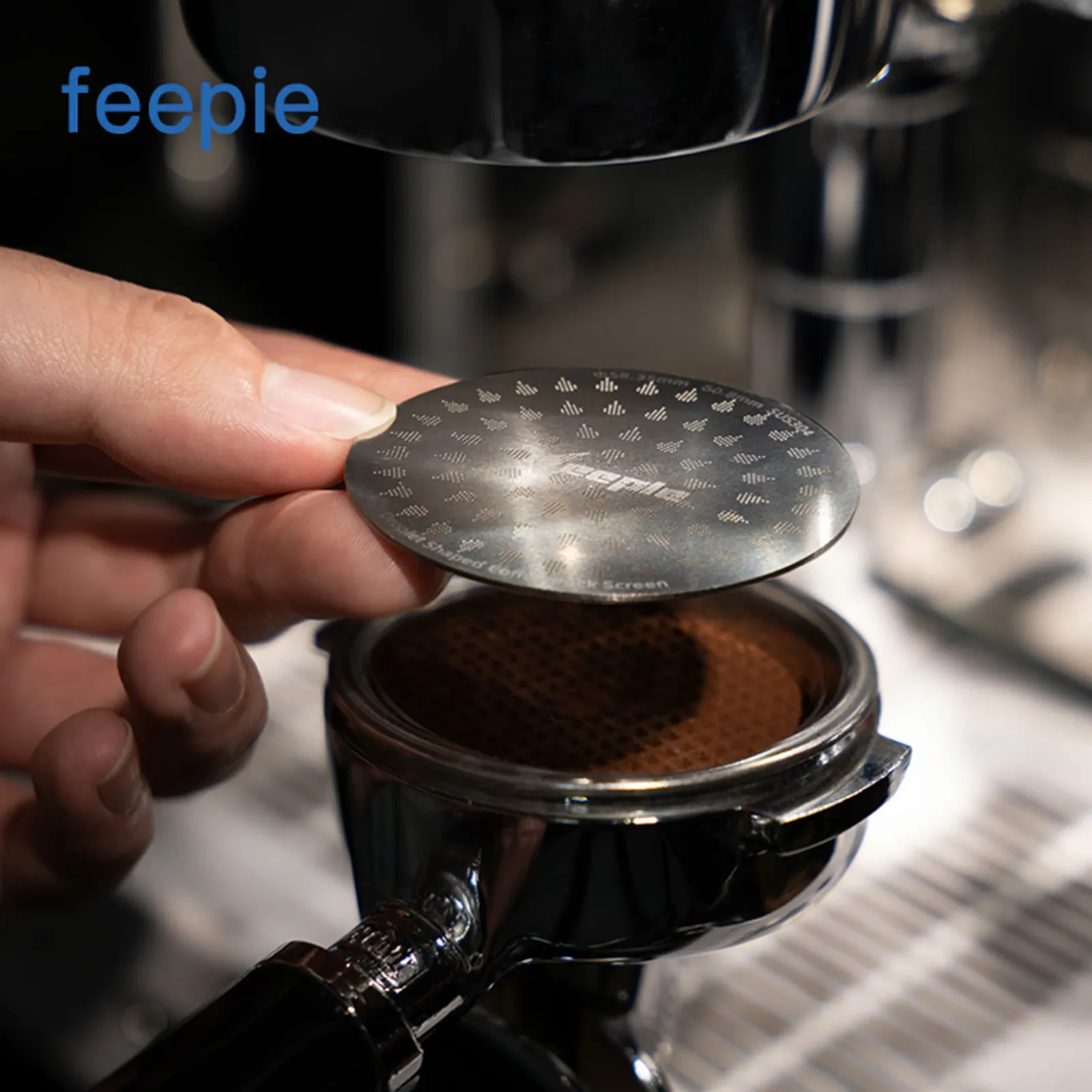 Barista đặt lưới lọc Feepie lên mặt bột cà phê đã nén trong tay cầm