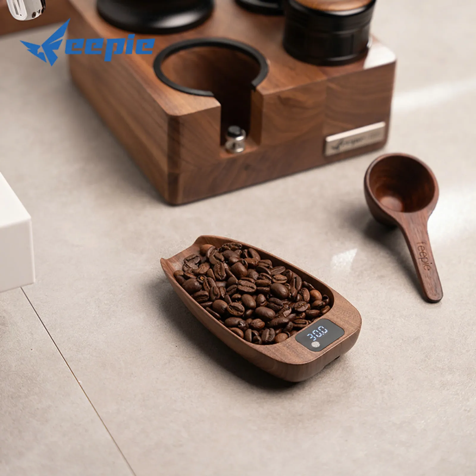 Cân điện tử khay gỗ Feepie đựng đầy hạt cà phê hiện 250g bên cạnh đế gỗ và muỗng đong