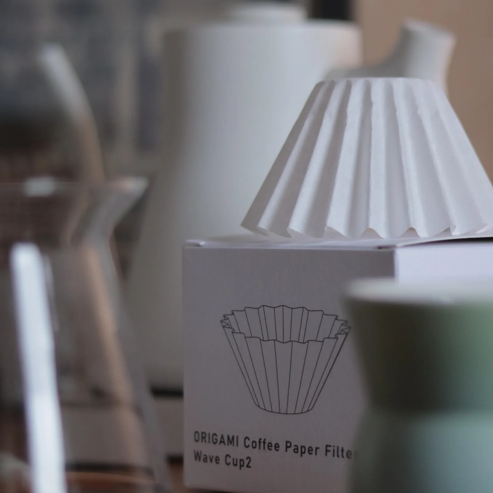 Giấy lọc Wave Origami cùng hộp, ấm rót cổ ngỗng và ly cà phê trên bàn
