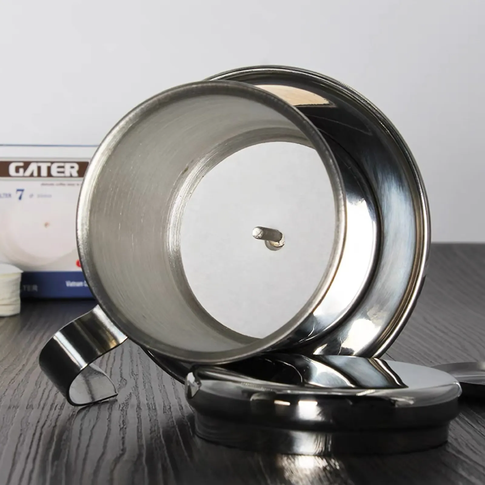 Nhìn từ trên xuống phin cà phê inox đặt trên ly thuỷ tinh thấy rõ đĩa nén và lòng phin