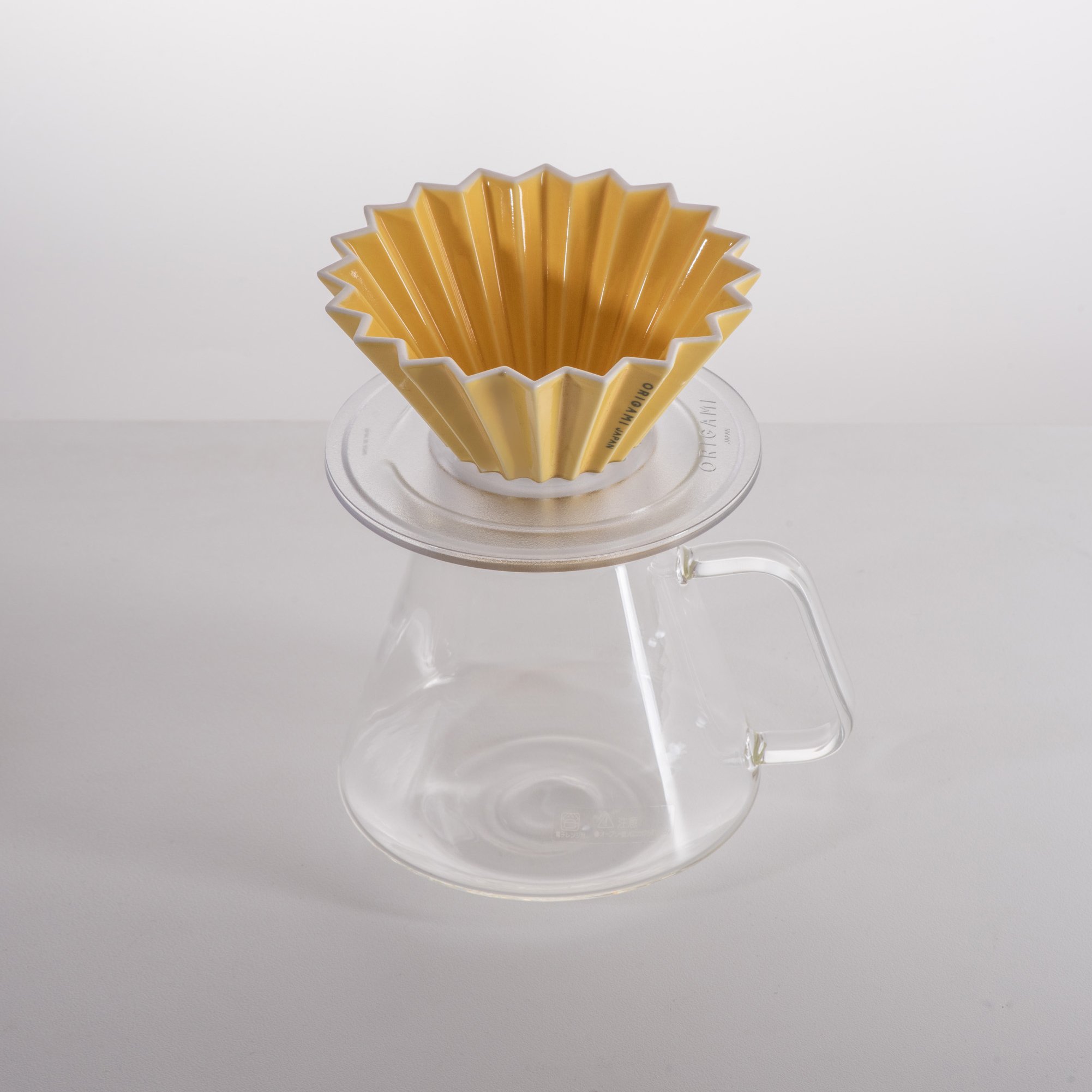 Phễu sứ Origami Dripper M màu vàng đồng đặt trên bình thuỷ tinh Origami x Hario 710ml nền trắng