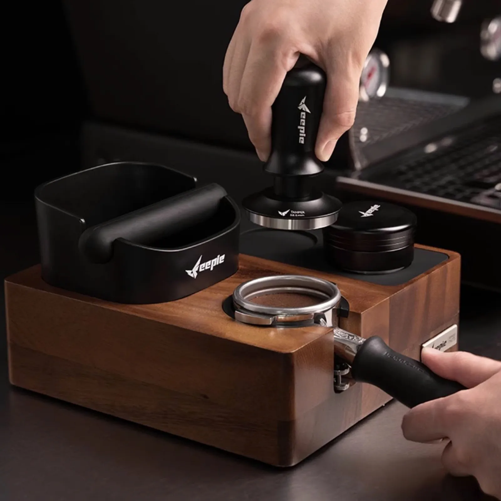 Barista nén bột bằng tamper trên bàn đế nén Feepie, tay cầm nằm trong khe nén
