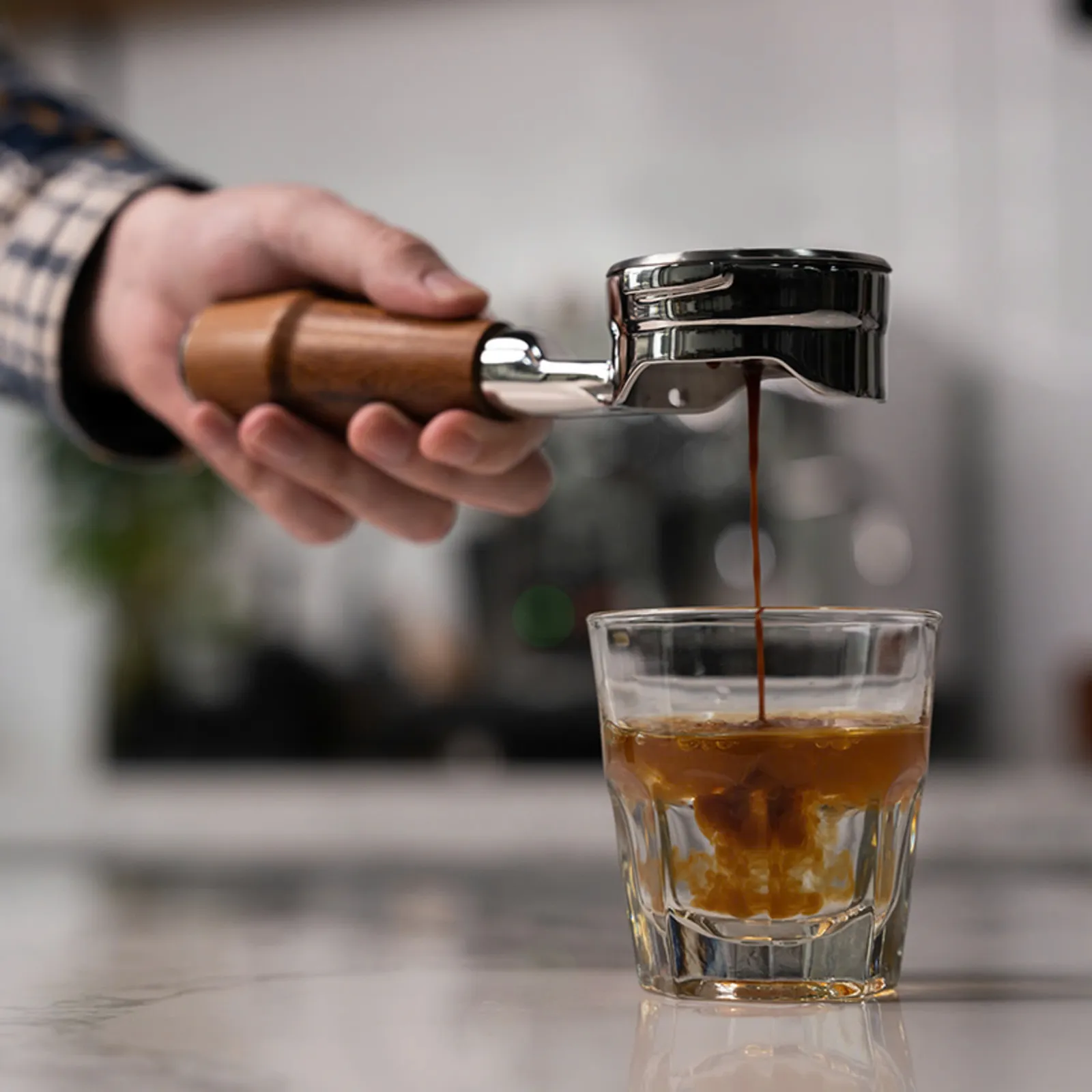 Espresso chảy thành dòng qua tay cầm gỗ Feepie không đáy xuống ly thuỷ tinh