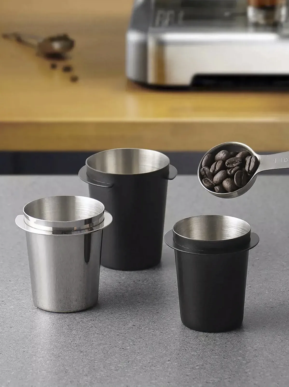 So sánh ba ly dosing cup inox và đen cùng muỗng đong cà phê trên bàn