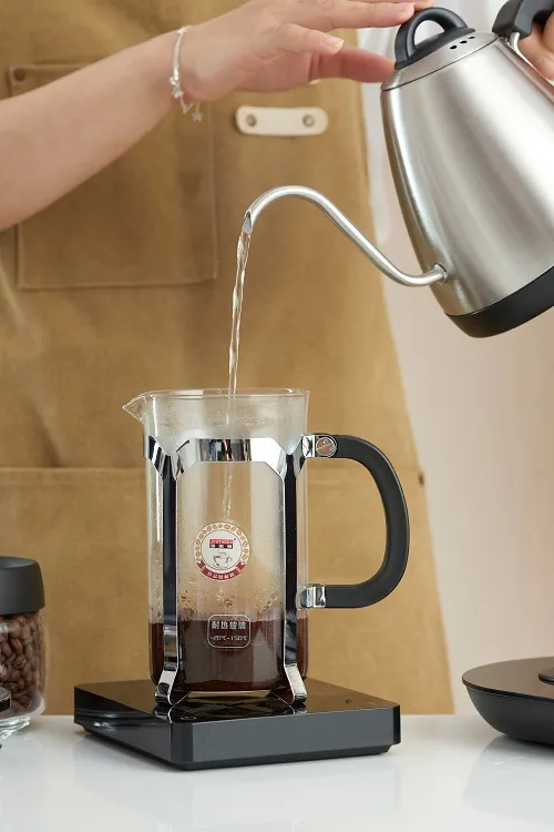 Rót nước nóng từ ấm cổ ngỗng inox vào bình French Press chứa bột cà phê