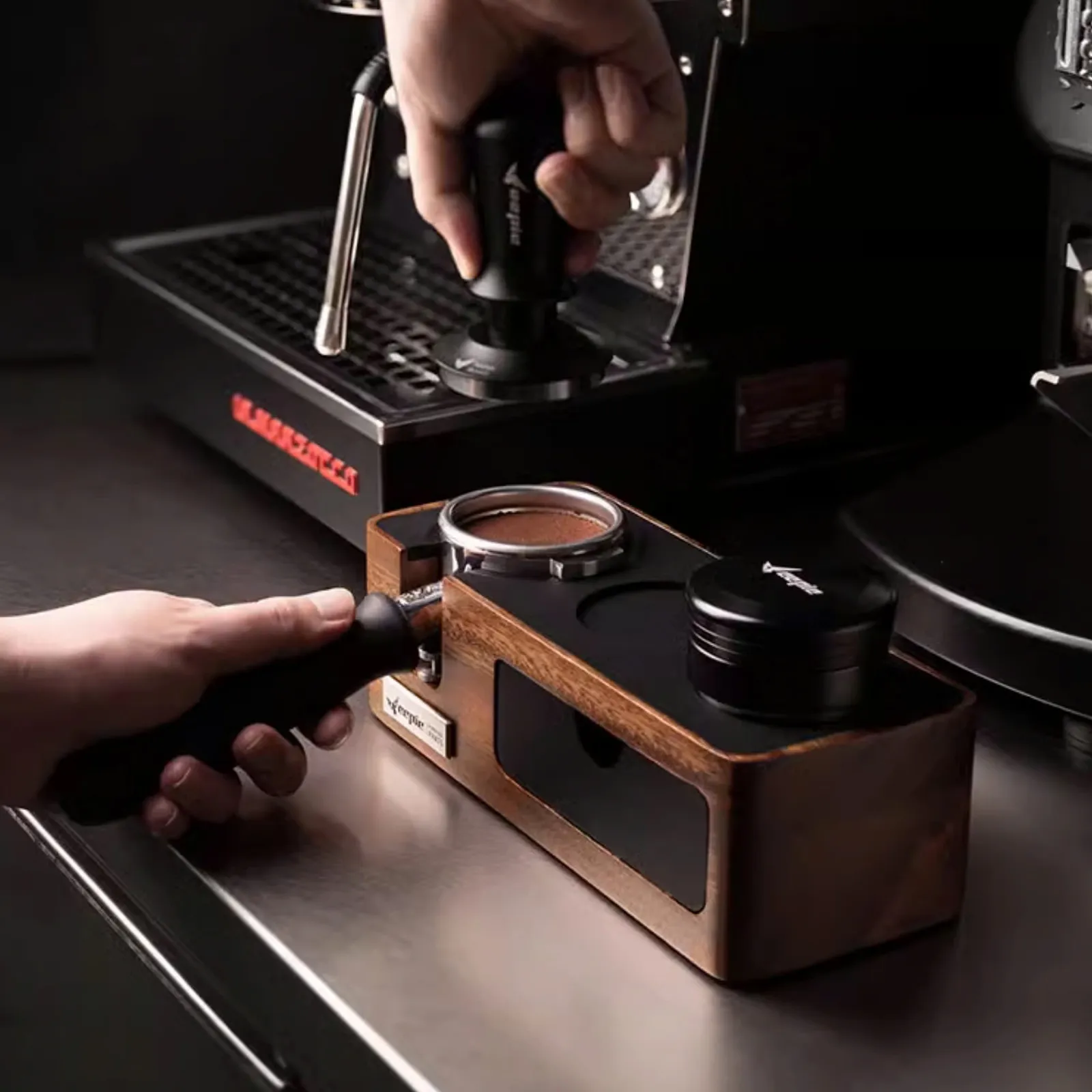 Barista đưa tay cầm portafilter vào đế nén Feepie trước khi lắp vào máy pha