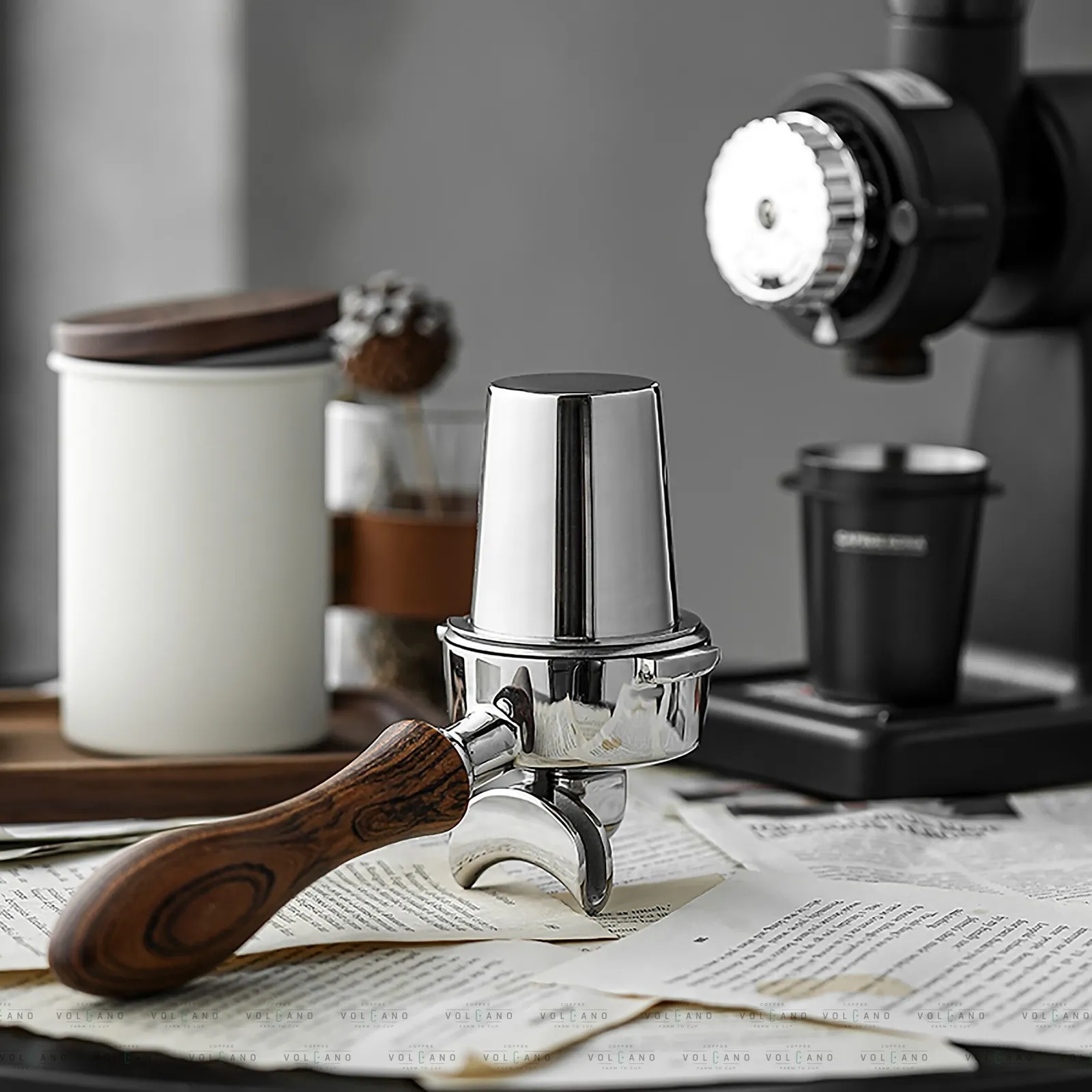 Ly dosing cup inox đặt cạnh máy xay và hũ đựng cà phê trên quầy bar