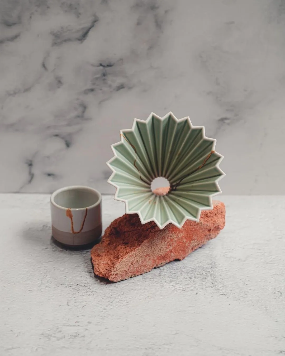 Phễu sứ Origami Dripper S màu Matte Green đặt cạnh ly sứ trên nền đá
