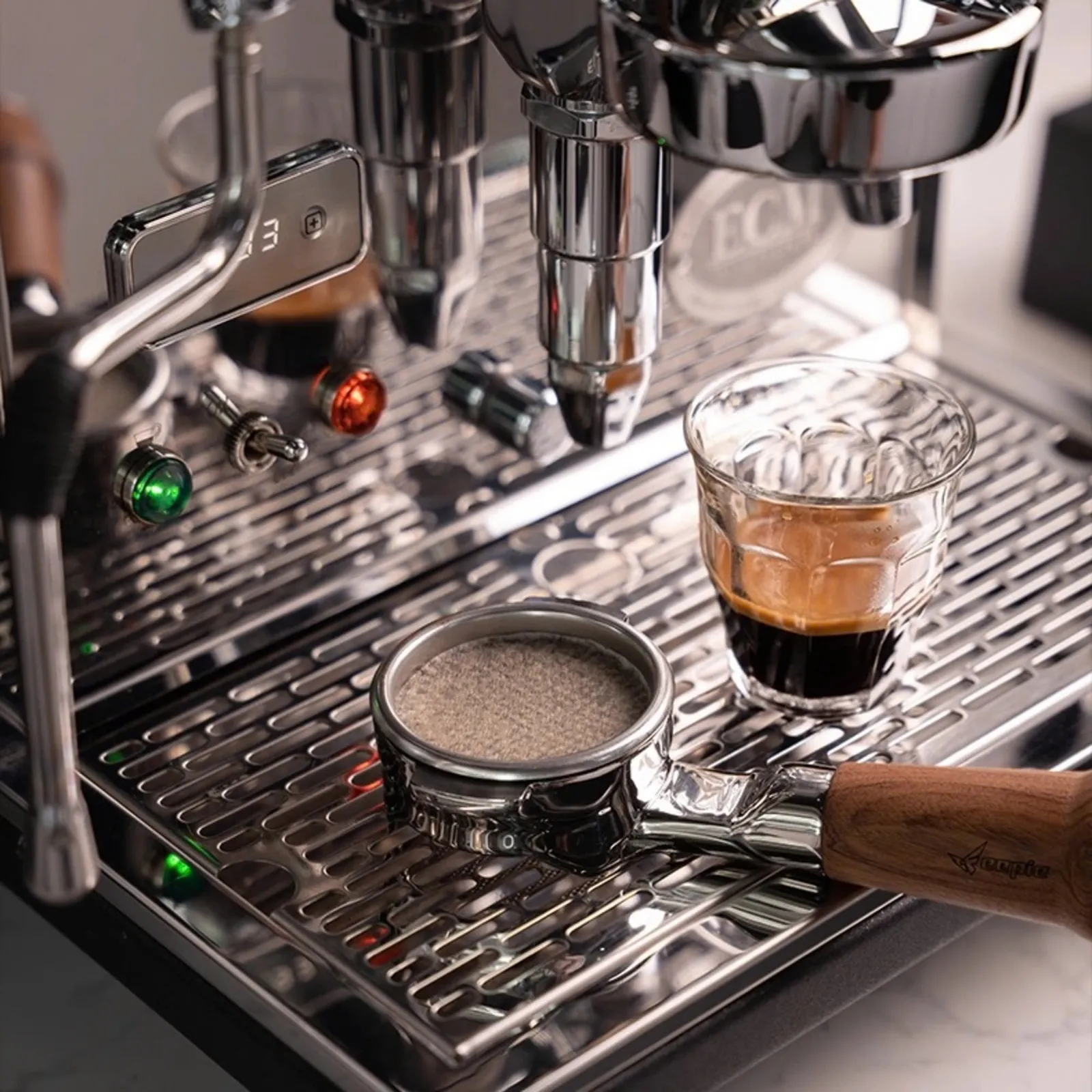 Tay cầm portafilter đặt cạnh ly espresso trên máy pha cà phê chuyên nghiệp