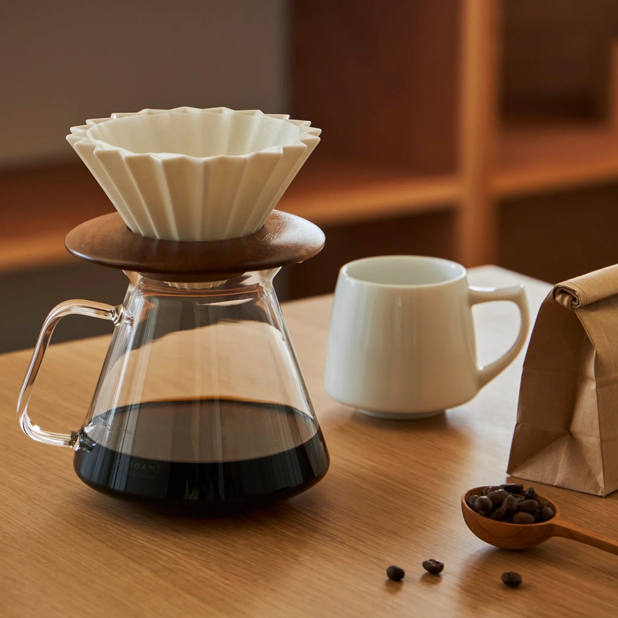 Bộ combo V60 Origami đặt trên bàn gỗ cùng ly cà phê và hạt cà phê rang