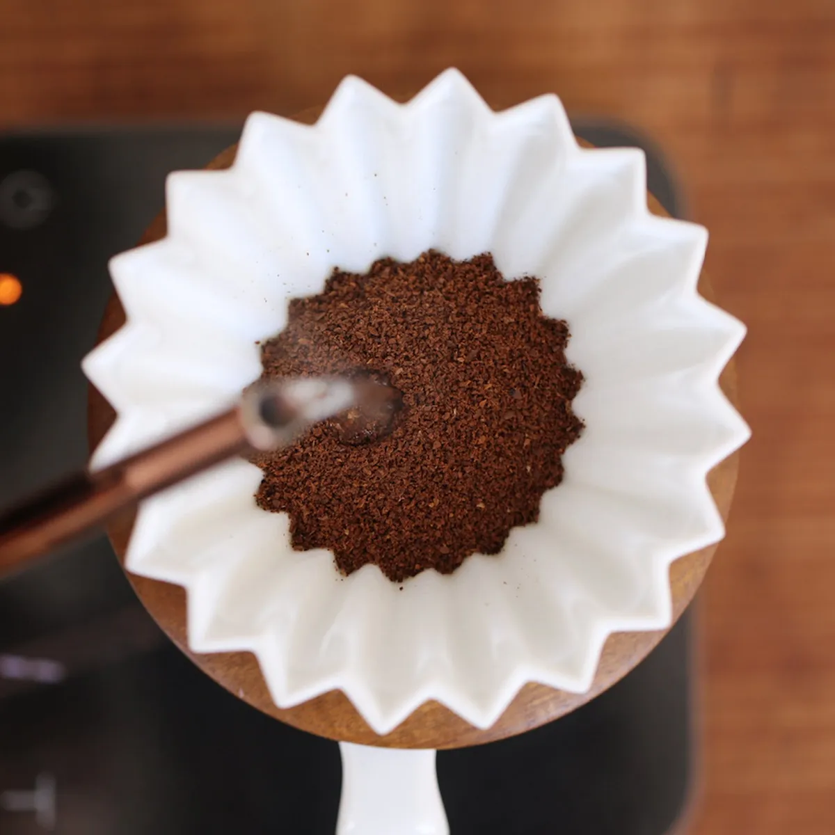 Phễu sứ Origami Dripper S màu trắng với giấy lọc và bột cà phê đã tán đều